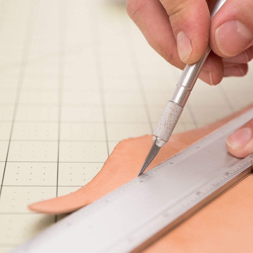 Cutting vegetable-tanned leather on a clean surface with an exacto blade and straight edge