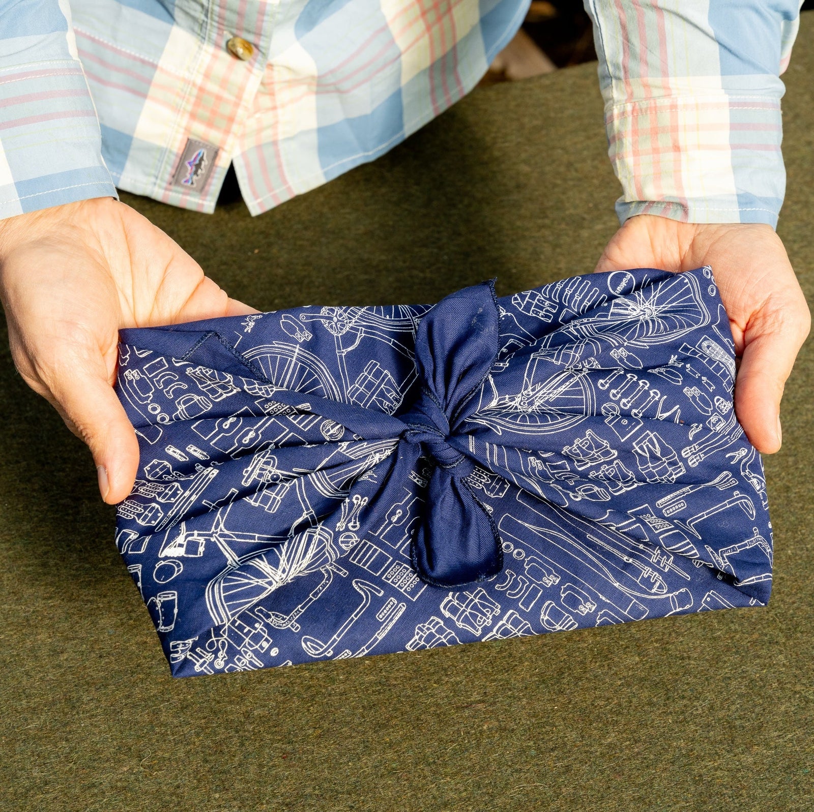 Looking down at a woman holding a gift wrapped in a blue and white bandana using Japanese furoshiki cloth folding art