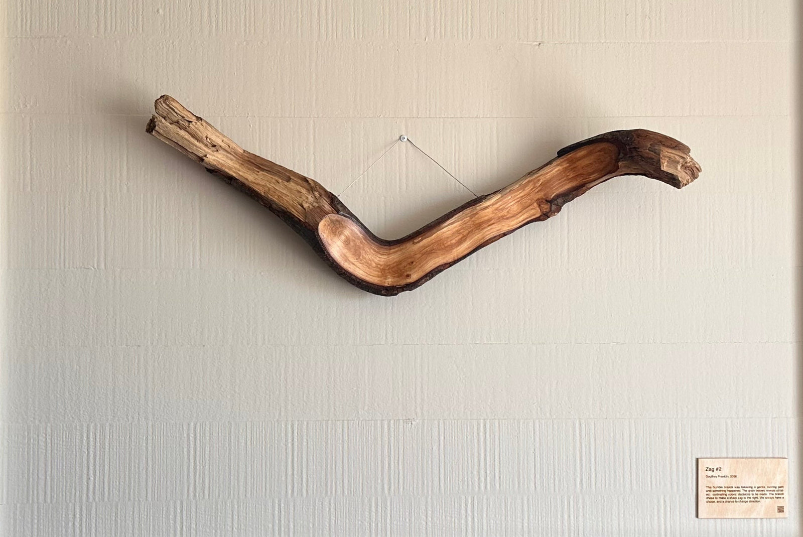 Wooden wall art piece on a white wall above a fireplace.