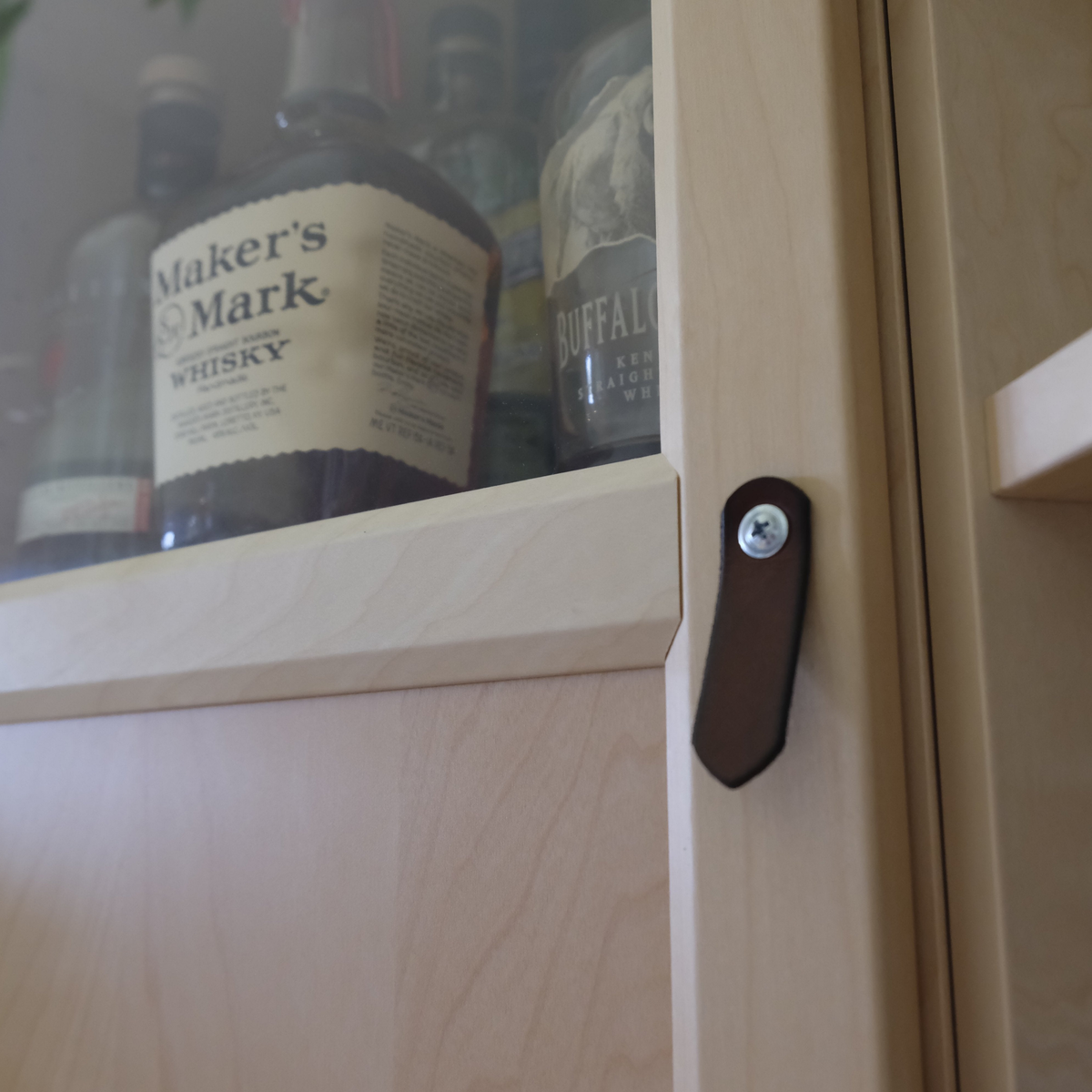 Side view of the St. Johns leather pull, with the door open, showing the handle was sold with no hardware and was secured directly into the door with a wood screw. Taken from a front angle.