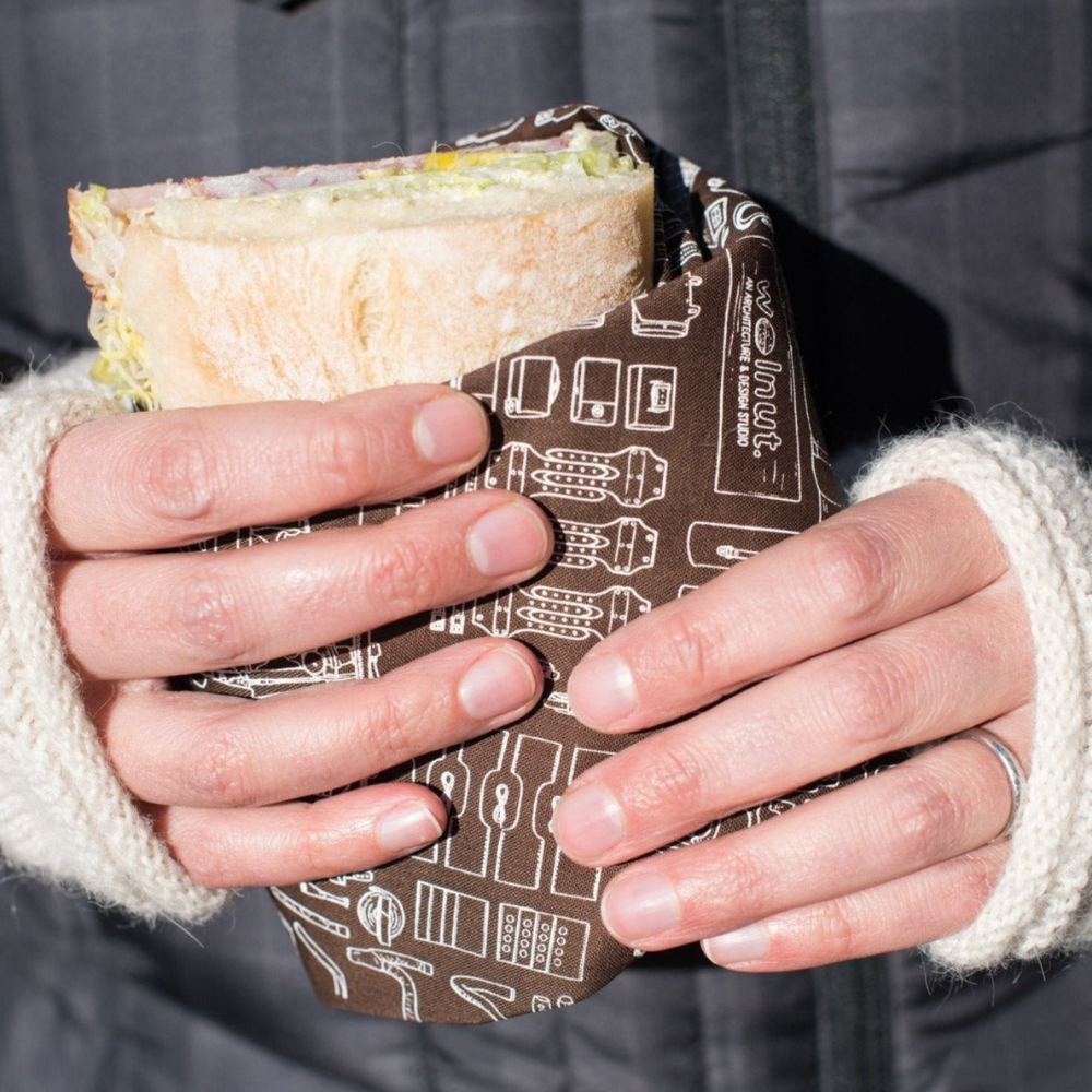 Hands holding a sandwich wrap wrapped in brown bicycle print bandana
