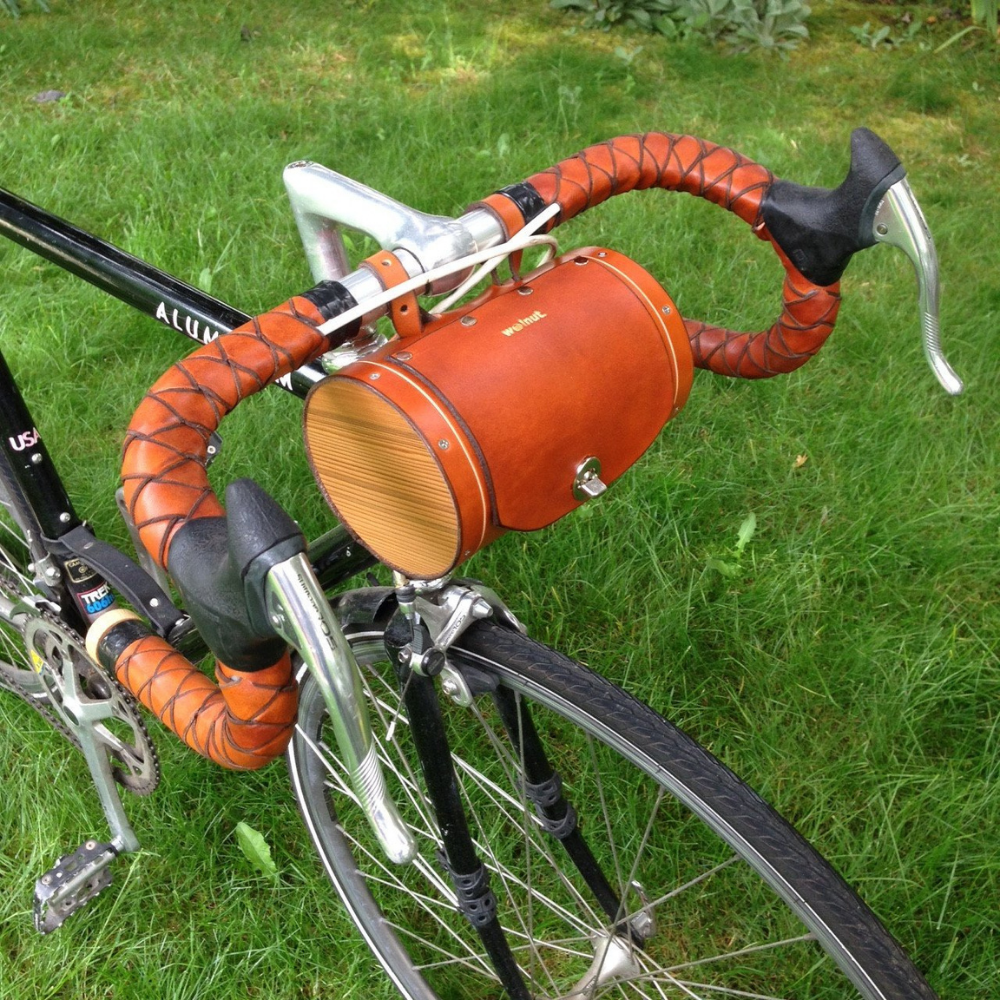 Side view of honey leather bag showcasing the wooden end pieces displayed on bicycle handlebars