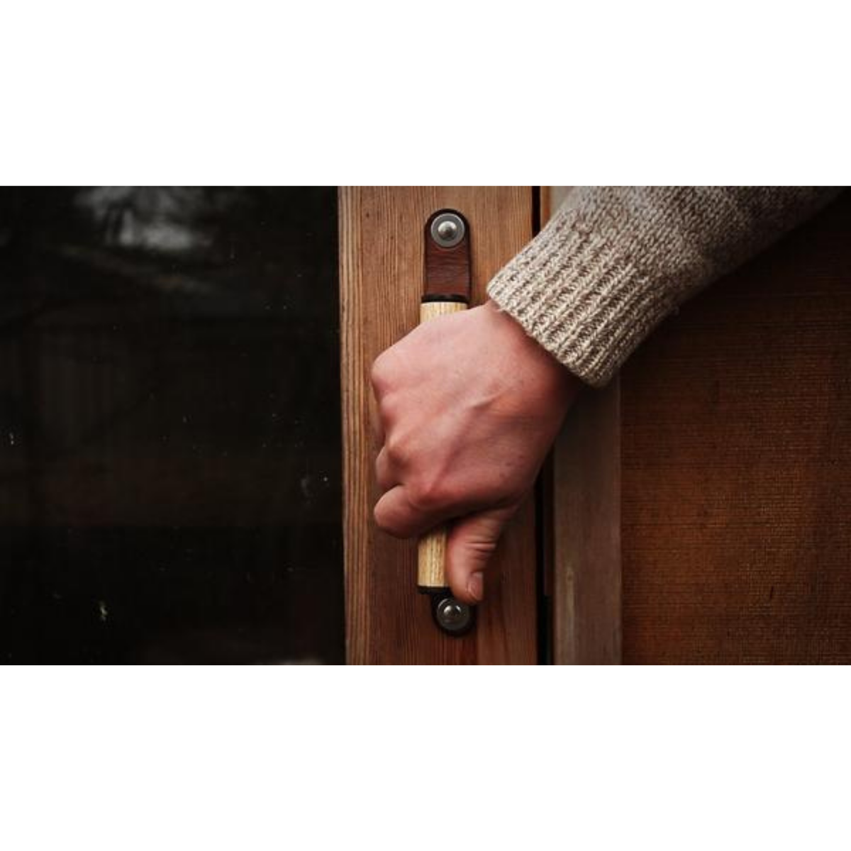 Man reaching to a Sellwood leather handle on a cedar wood sauna door outside