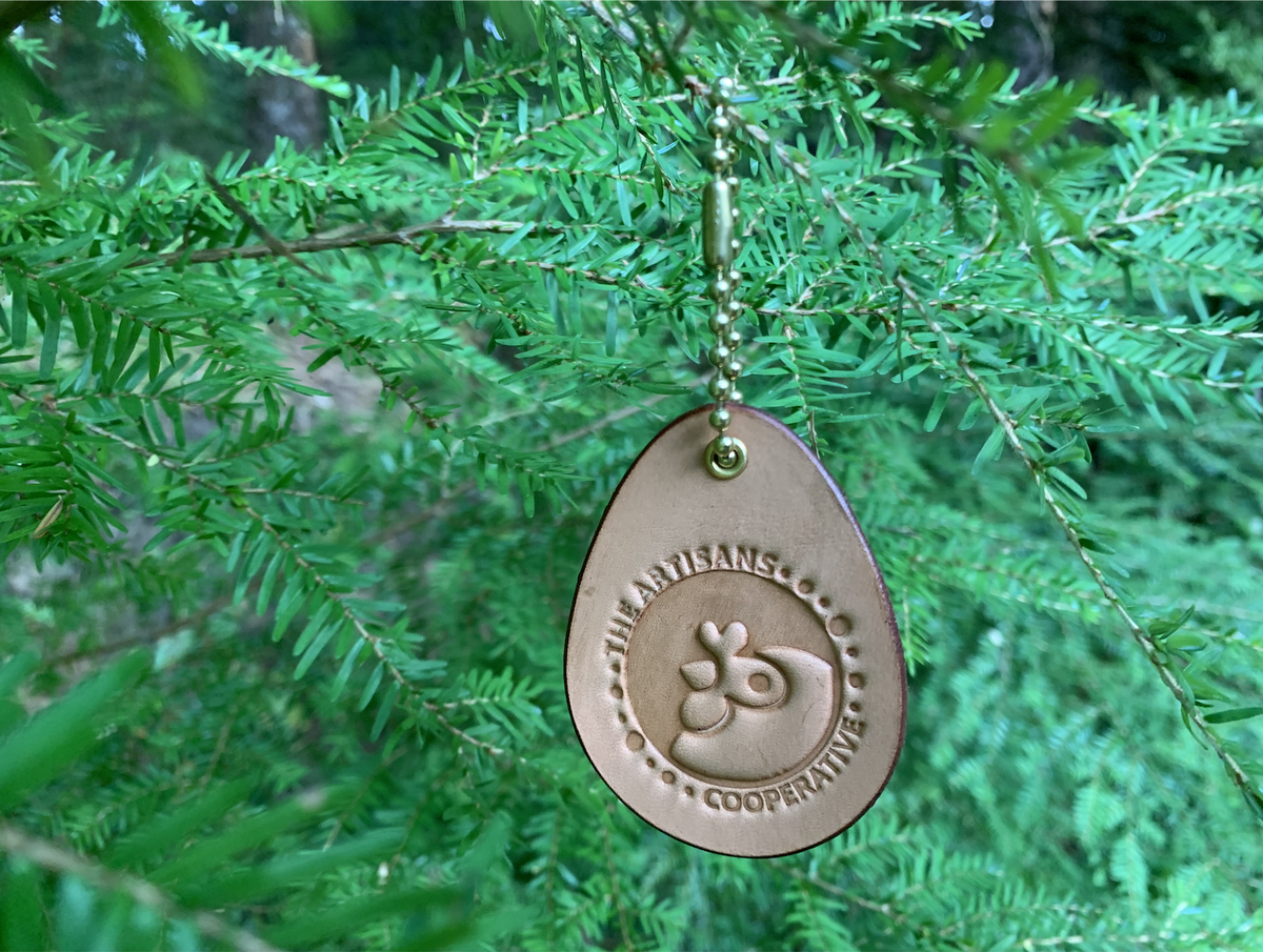 Leather fundraiser for Artisans Cooperative hung from a tree like a Christmas ornament