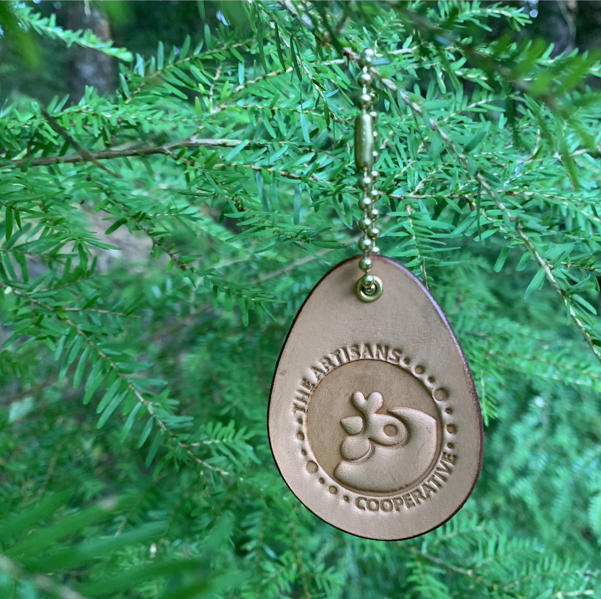Leather fundraiser for Artisans Cooperative hung from a tree like a Christmas ornament