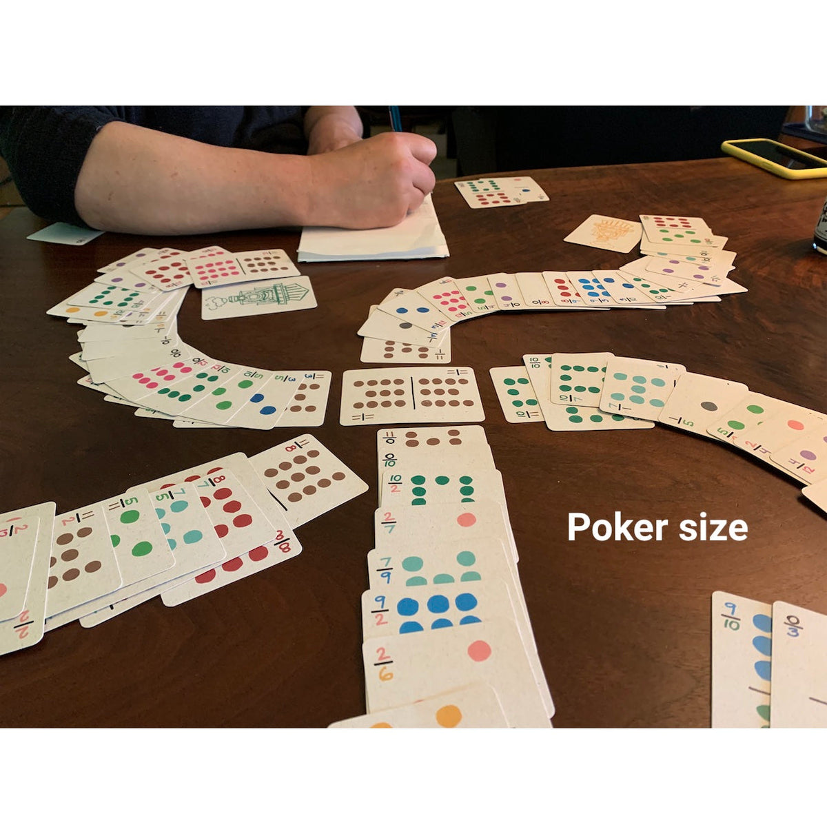 Travel dominoes in the larger poker size on a table with two people playing