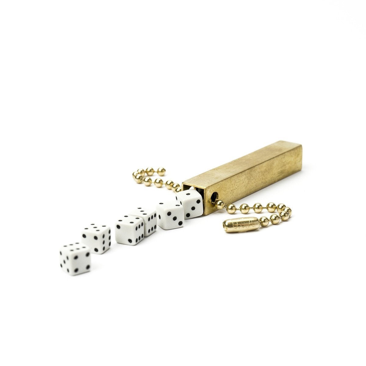 White background variant photo of brass travel dice with white dice and a keychain