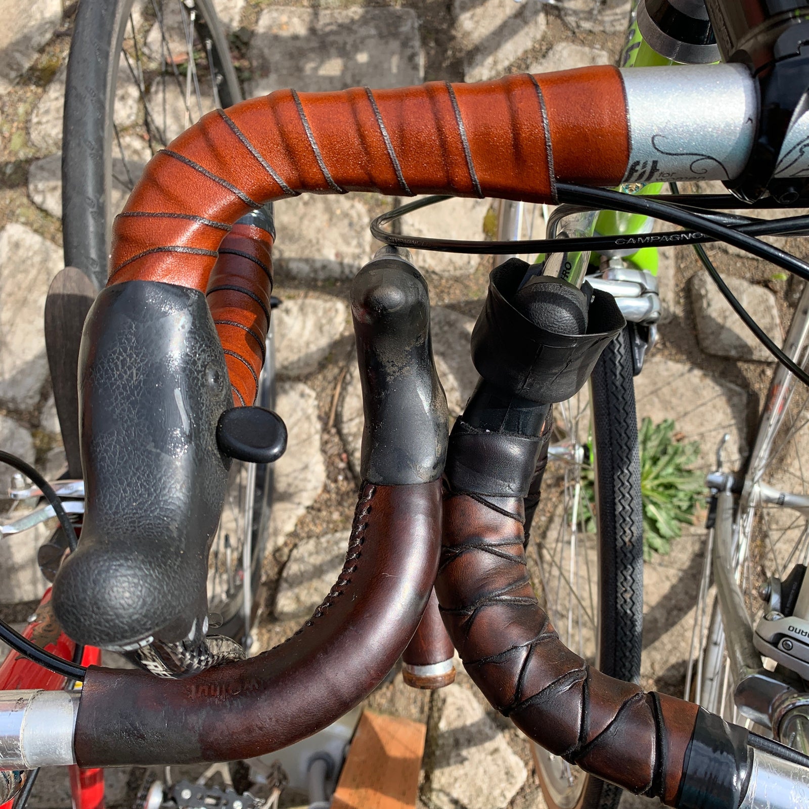 Three leather bicycle handlebars with leather wraps next to each other