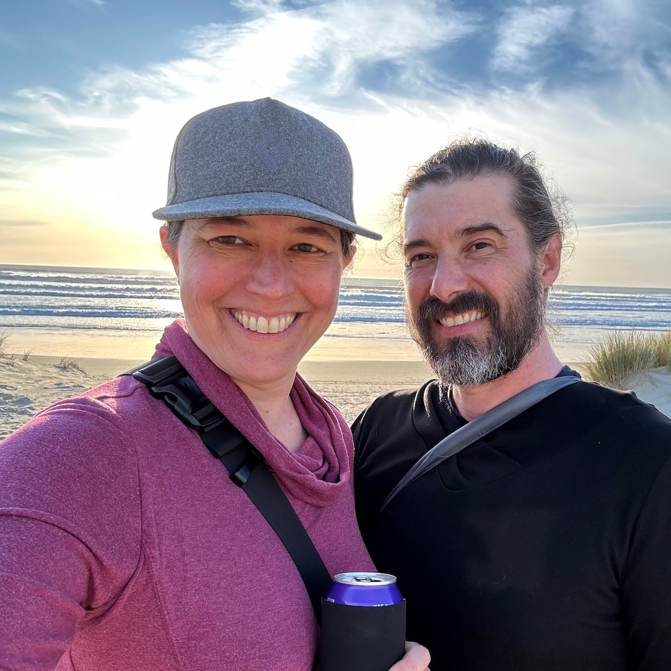 Selfie of Valerie and Geoffrey Franklin from Walnut Studiolo on Manzanita beach on a cloudy day with blue sky and a peach sunset, taken in March 2024