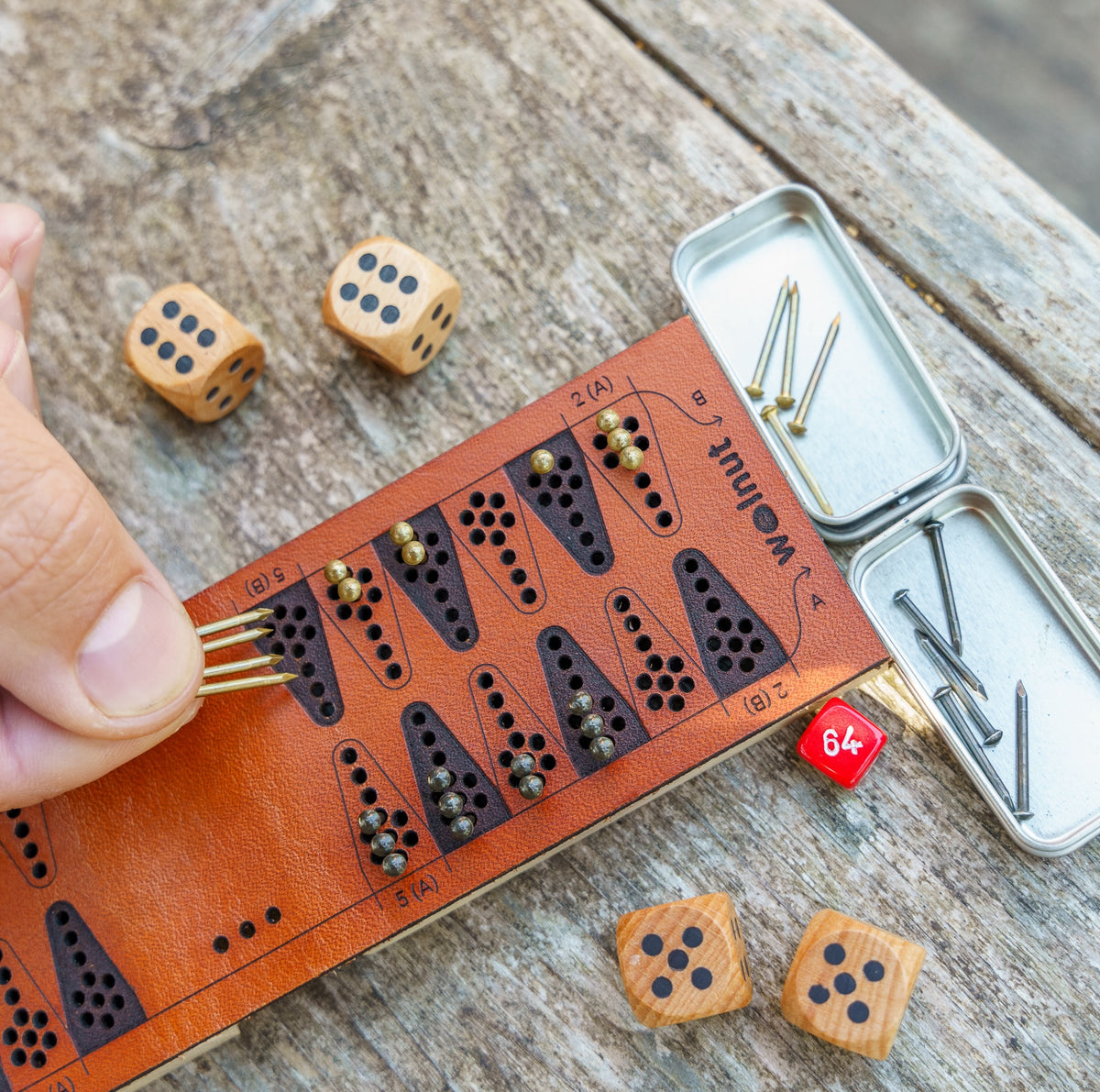 Close-up detail of a leather travel backgammon board laser quality and a man's hand moving four game pieces (nails) at once because he rolled a double 6 on the dice