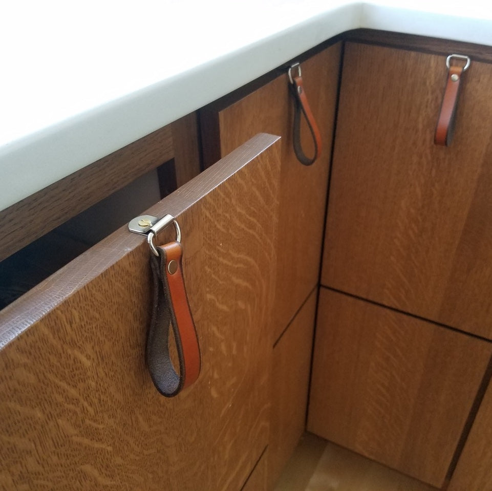 A kitchen countertop with a drawer below partially pulled out to see the top edge of the drawer showing an attached leather loop hinged handle
