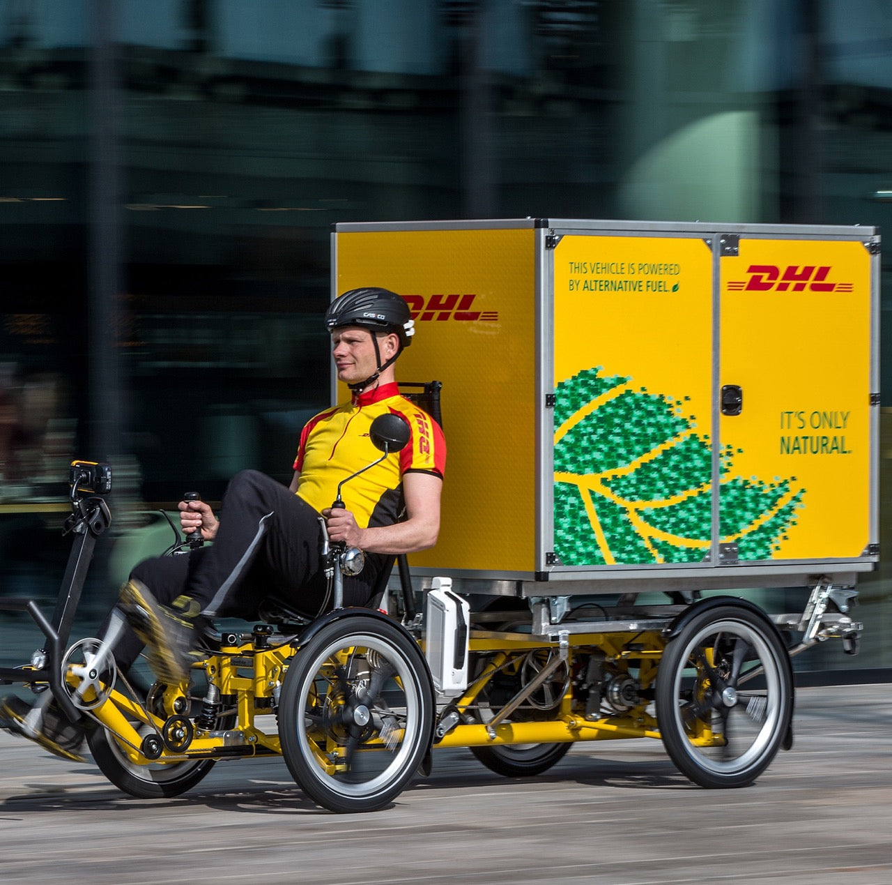 DHL Express delivery person riding a recumbent bicycle delivery with Christmas tree holiday graphics on the trailer