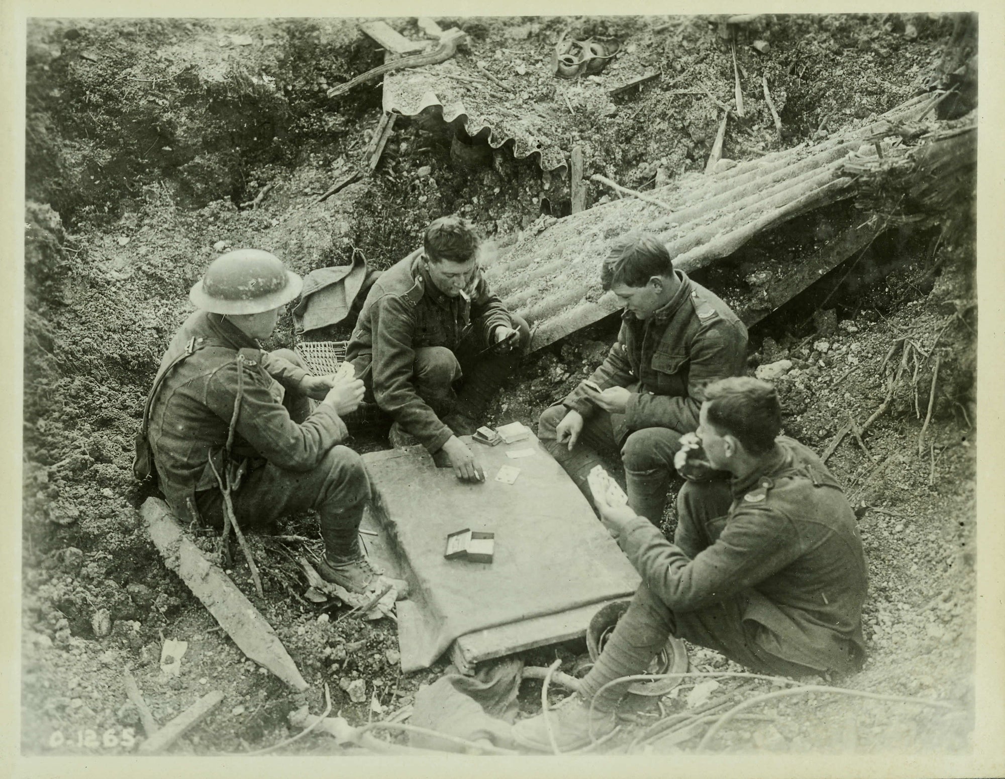 Historic photo of A group of Canadian soldiers enjoy a game of cards in a shell hole, no date, probably world War I. 