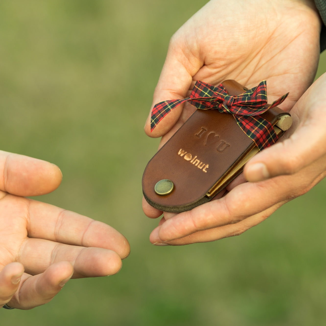 One set of hands offering a wrapped cribbage board as a gift, and another hand reaching out to accept the gift