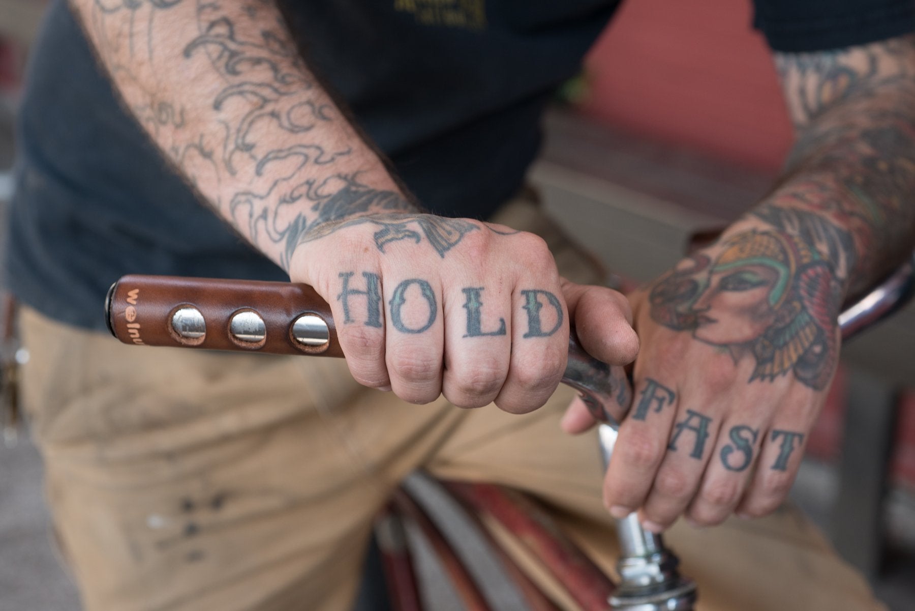 A man's hands with the 'Hold Fast' knuckle tattoo on dark brown leather bicycle grips model. Photo by Erin Berzel. 