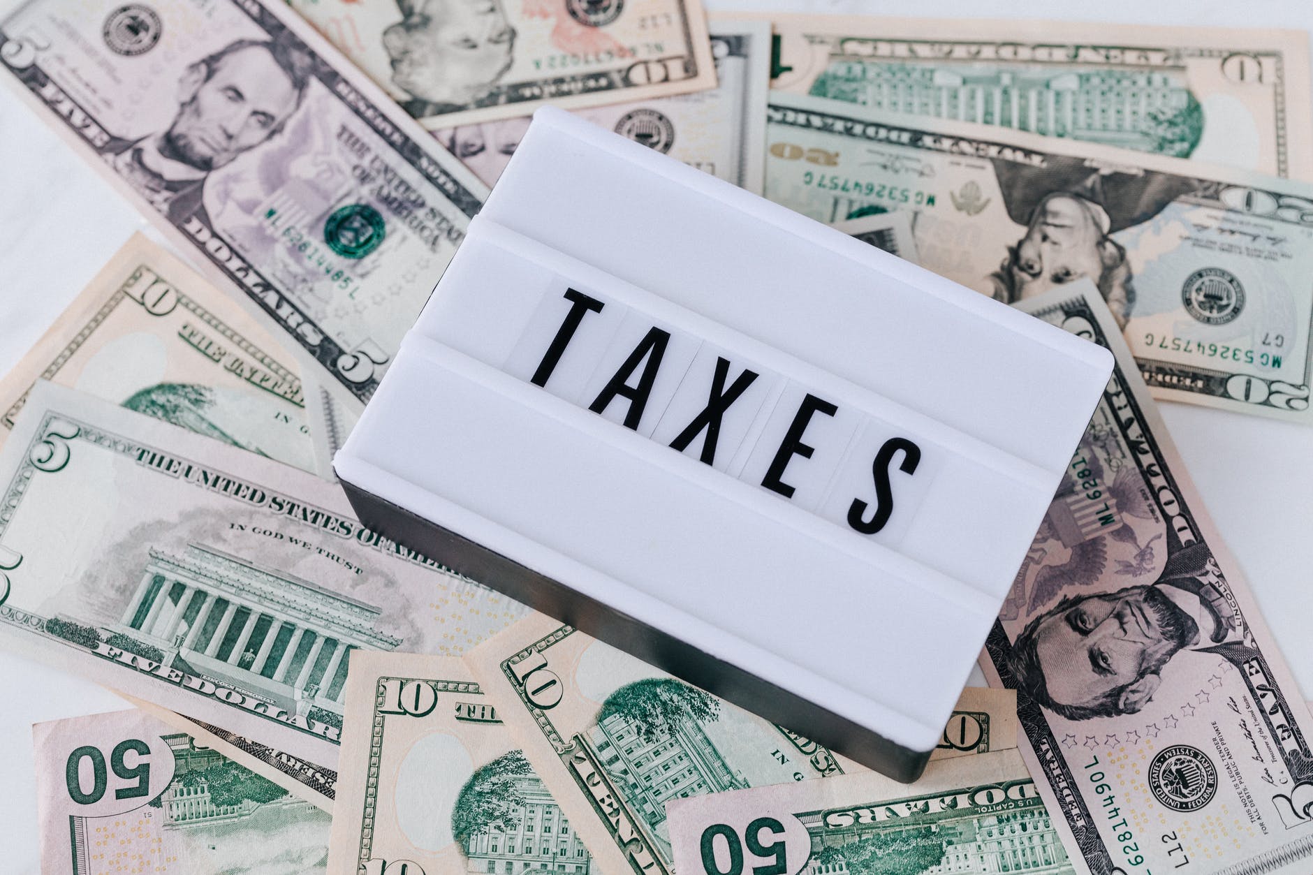 Stock image of a word board with the word taxes on top of a pile of US dollar bills