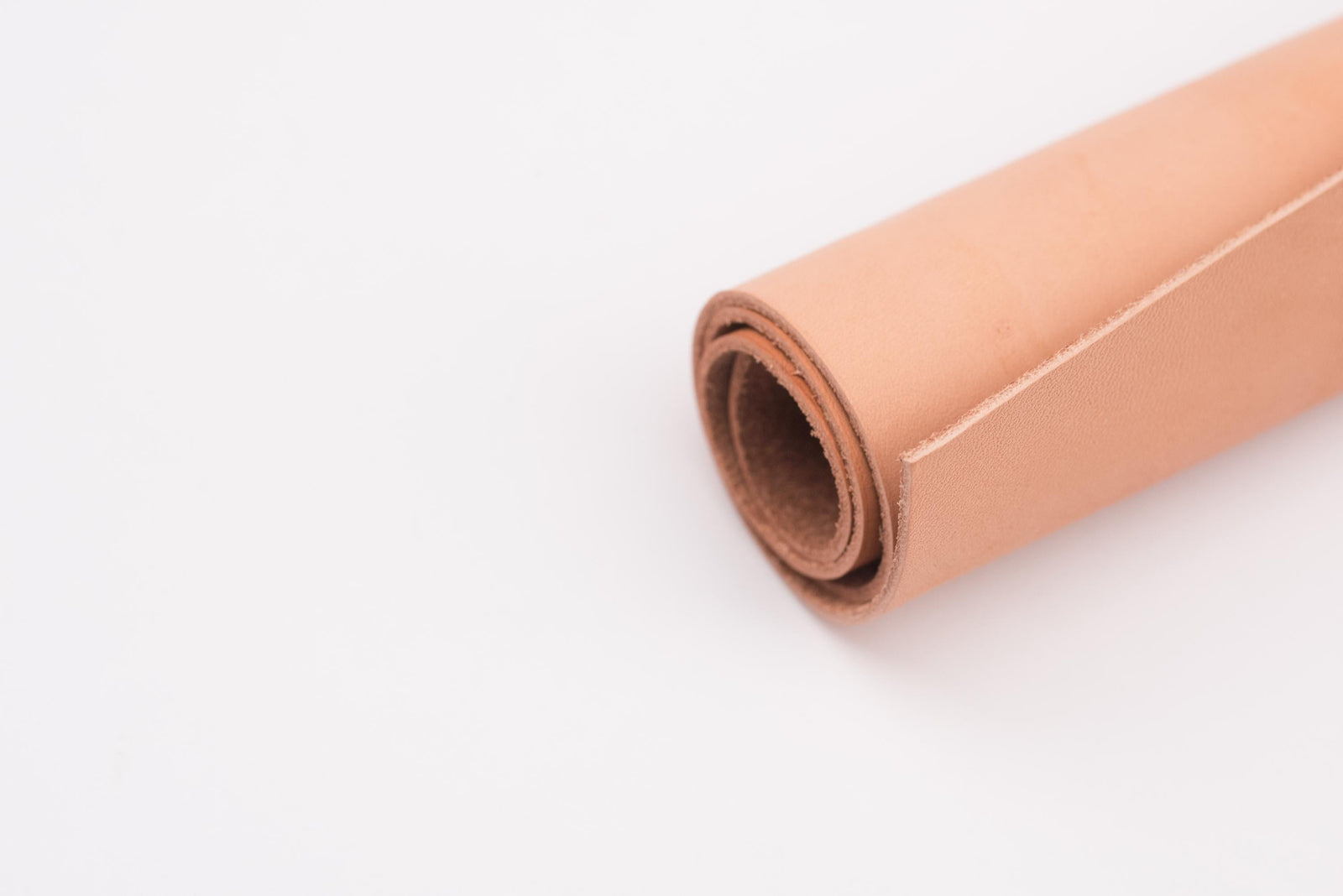 A roll of natural tooling leather on a white background