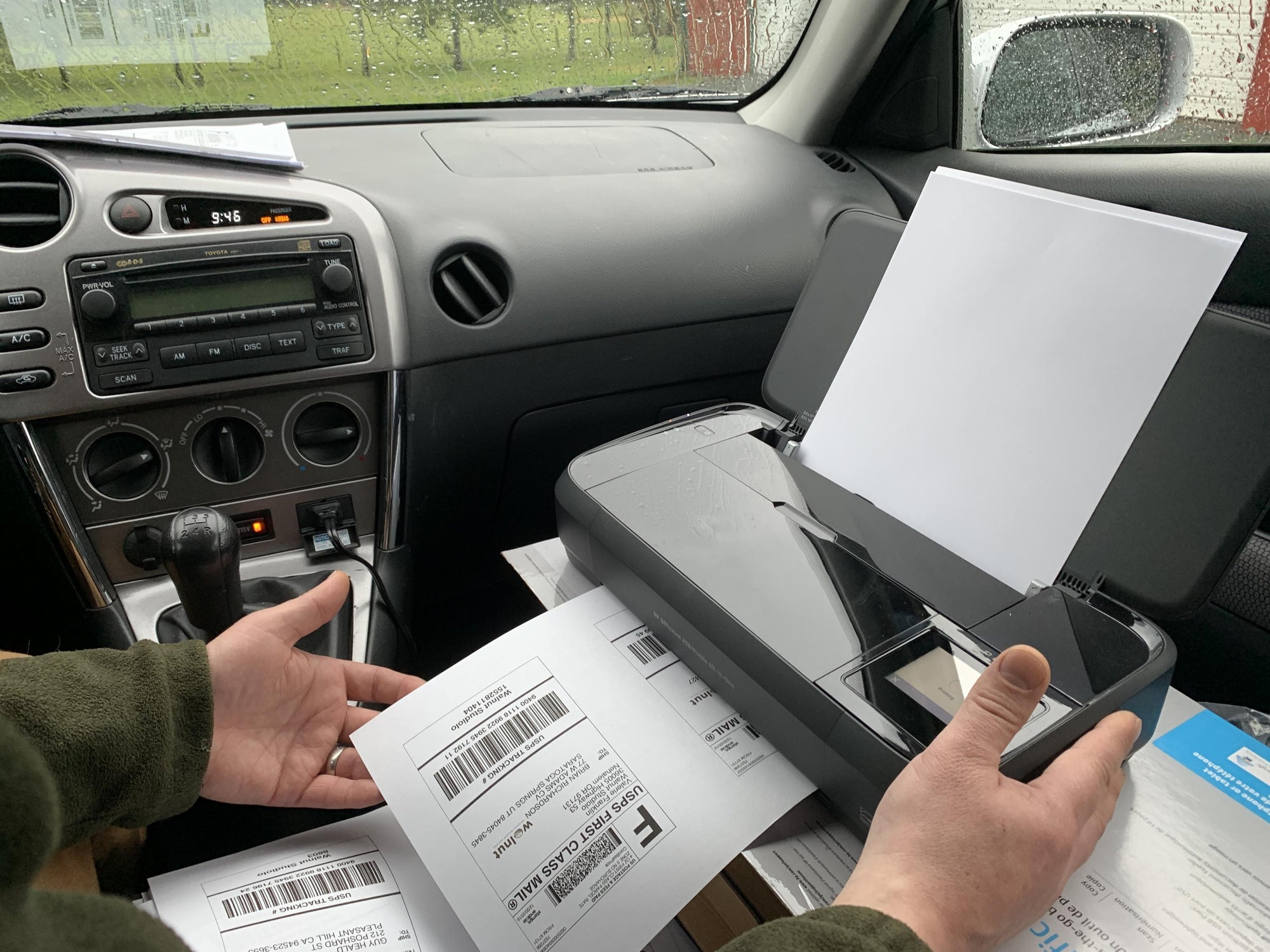 A mobile printer on the passenger seat of a car printing out shipping labels