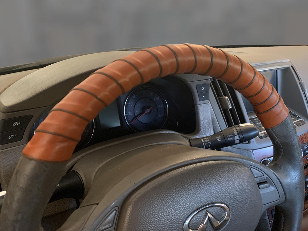 A car steering wheel wrapped in coiled-on honey leather from the interior of the car