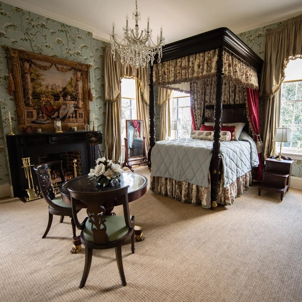 A richly-decorated bedroom with antiques, textiles, and furnishings reminscent of a historic royal castle in a modern American home with dark walnut wood and craftsmanship elements as well as antiques and reproductions