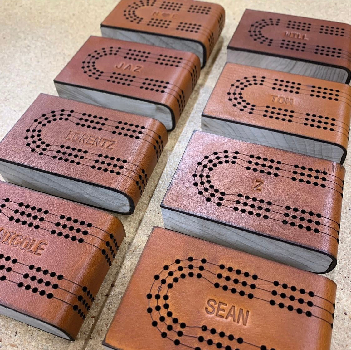 A neatly organized set of 8 travel cribbage boards, each with a unique groomsman wedding monograms for gifts