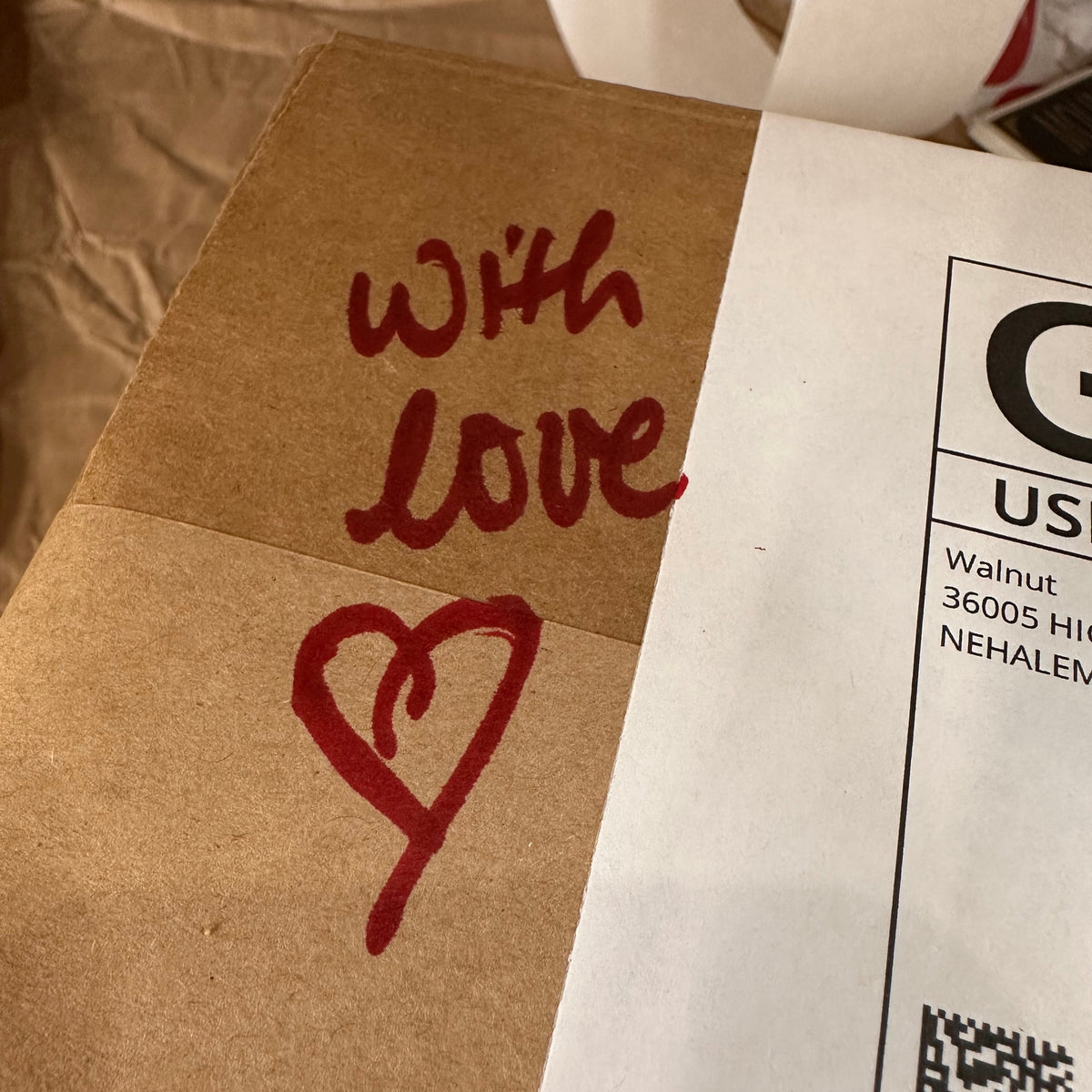 Cardboard shipping box with &#39;With Love&#39; text and a heart symbol on a white background