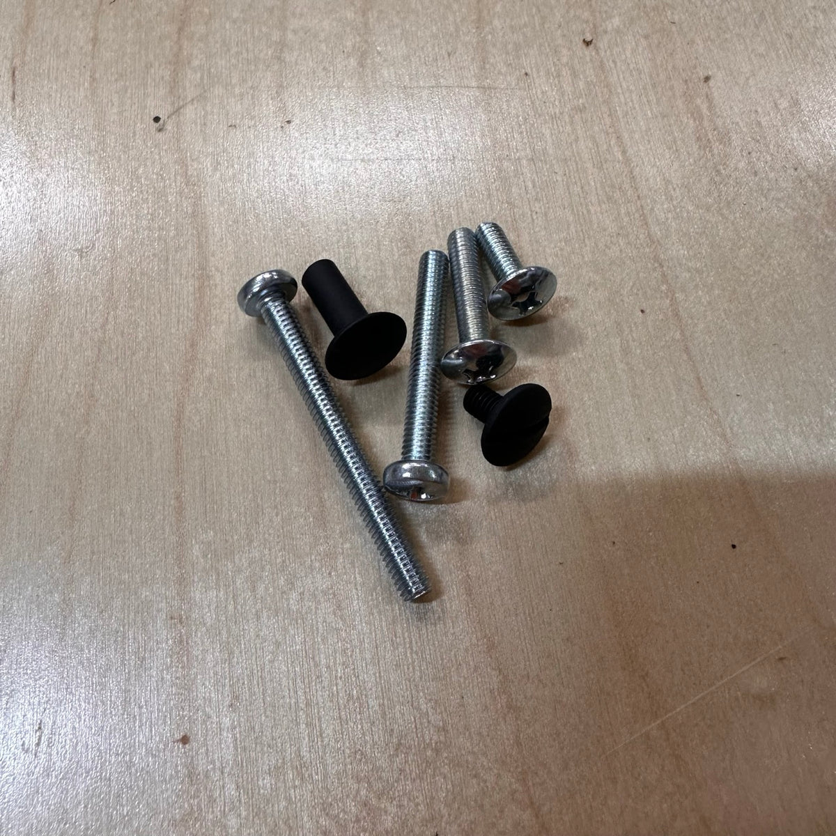 Set of screws on a wooden surface with Black Chicago screw and multiple sizes of zinc back screw