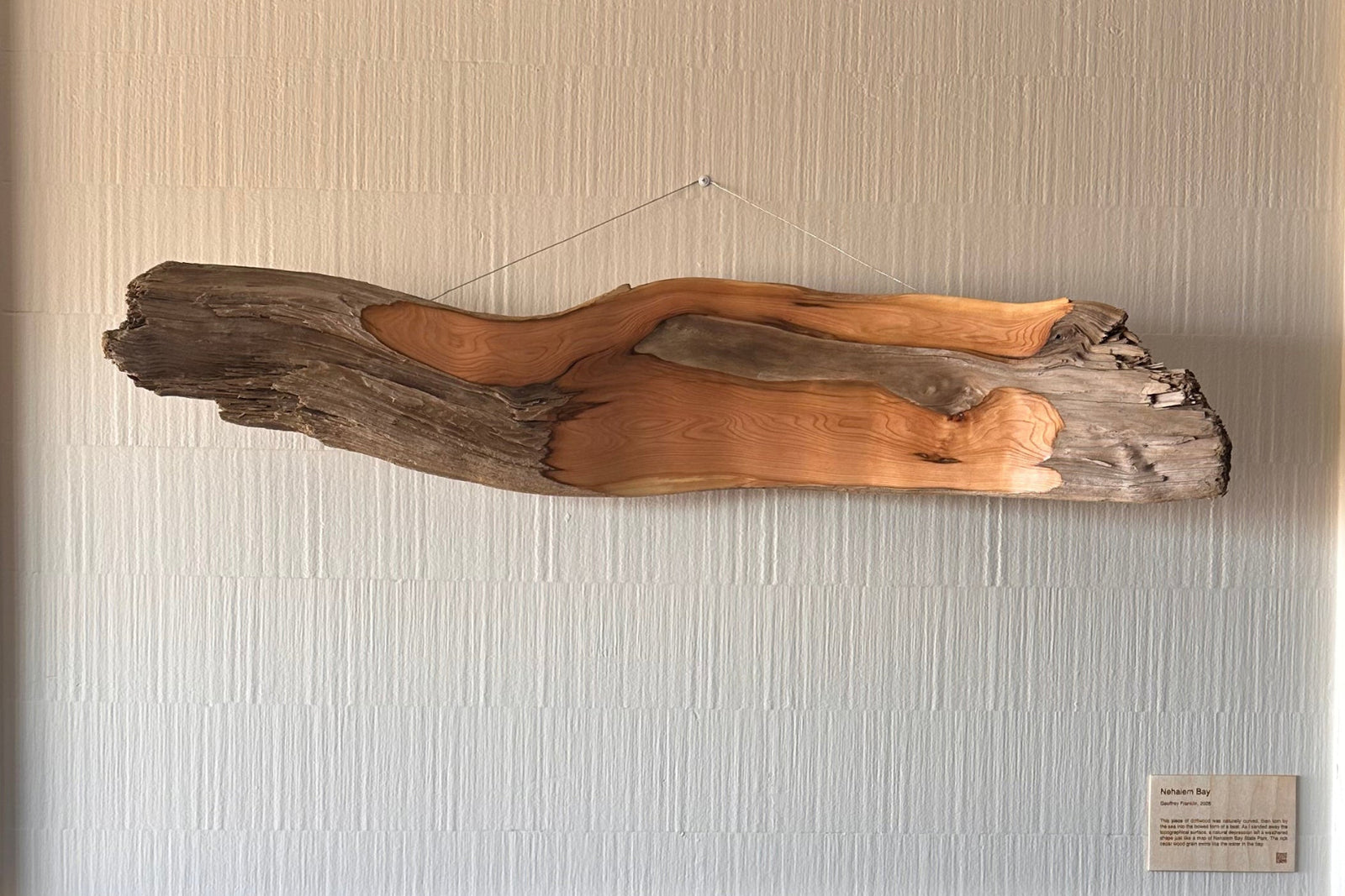 Fireplace with a driftwood art piece on a textured wall.