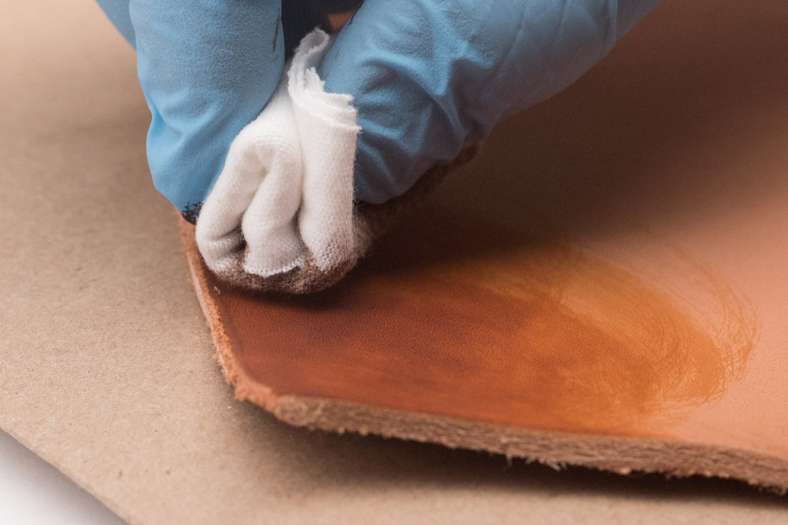 Close-up of a hand applying dye to natural leather