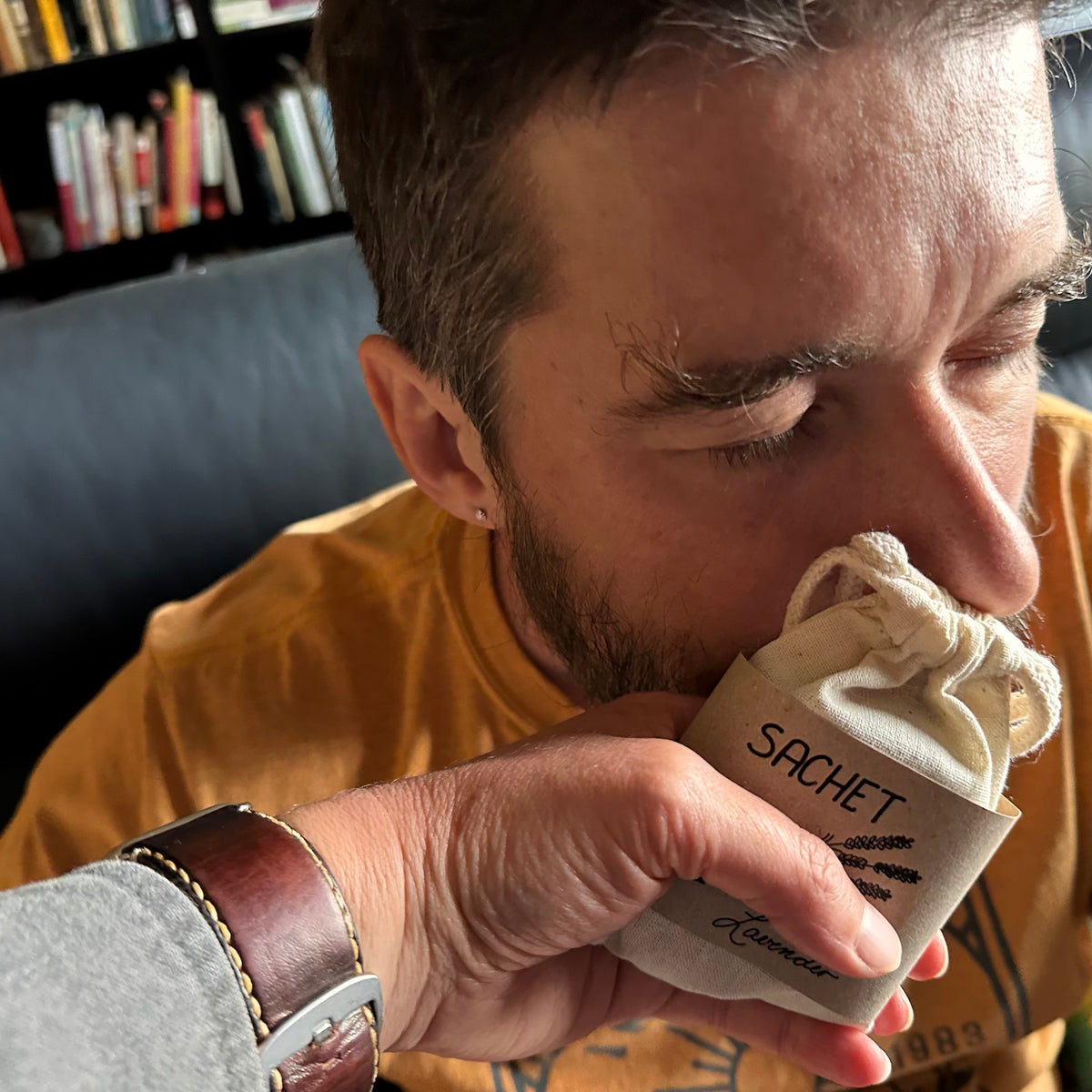 A man leaning in to smell a sachet bag with his eyes closed as he inhales the scent