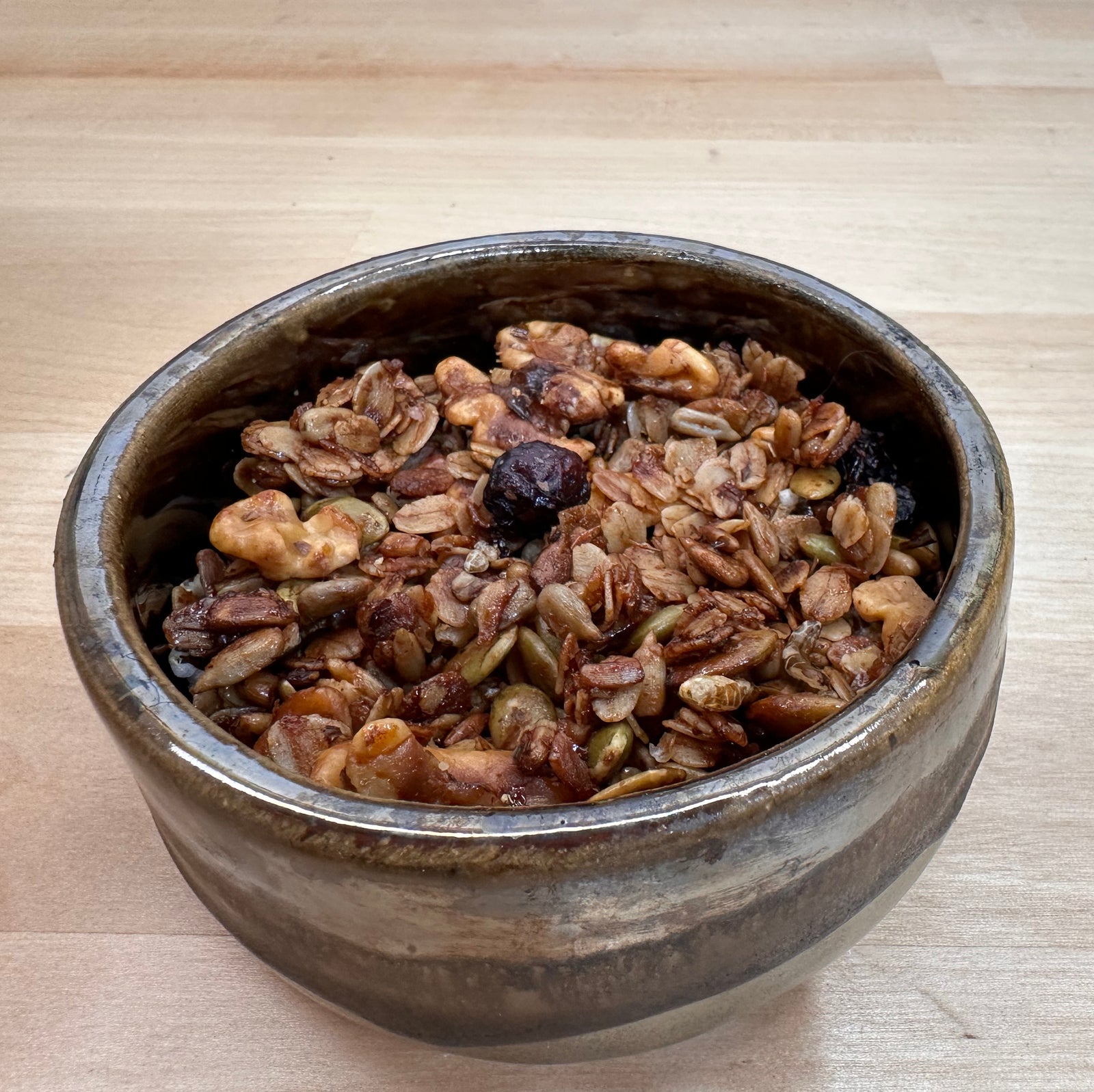 Bowl of granola with nuts and dried fruits on a wooden surface