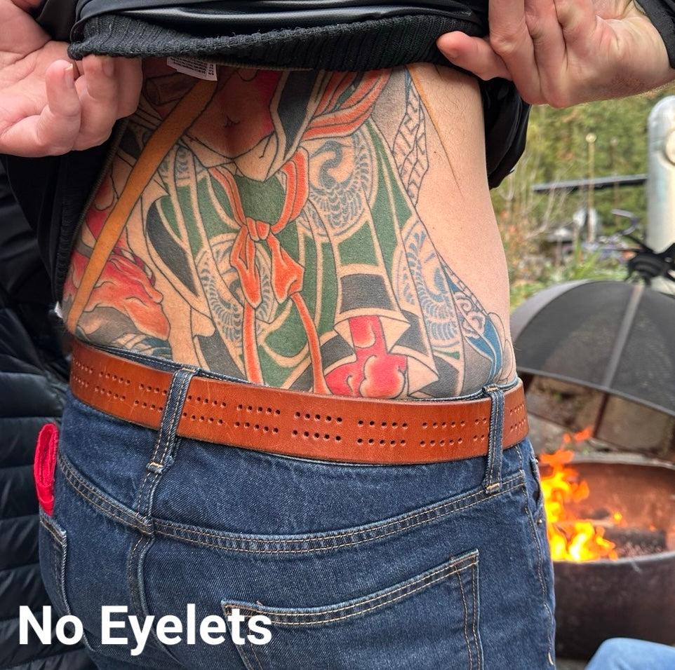 Person with a detailed colorful tattoo on their back wearing blue jeans and a brown cribbage board belt, standing near a fire pit, with the text, No Eyelets