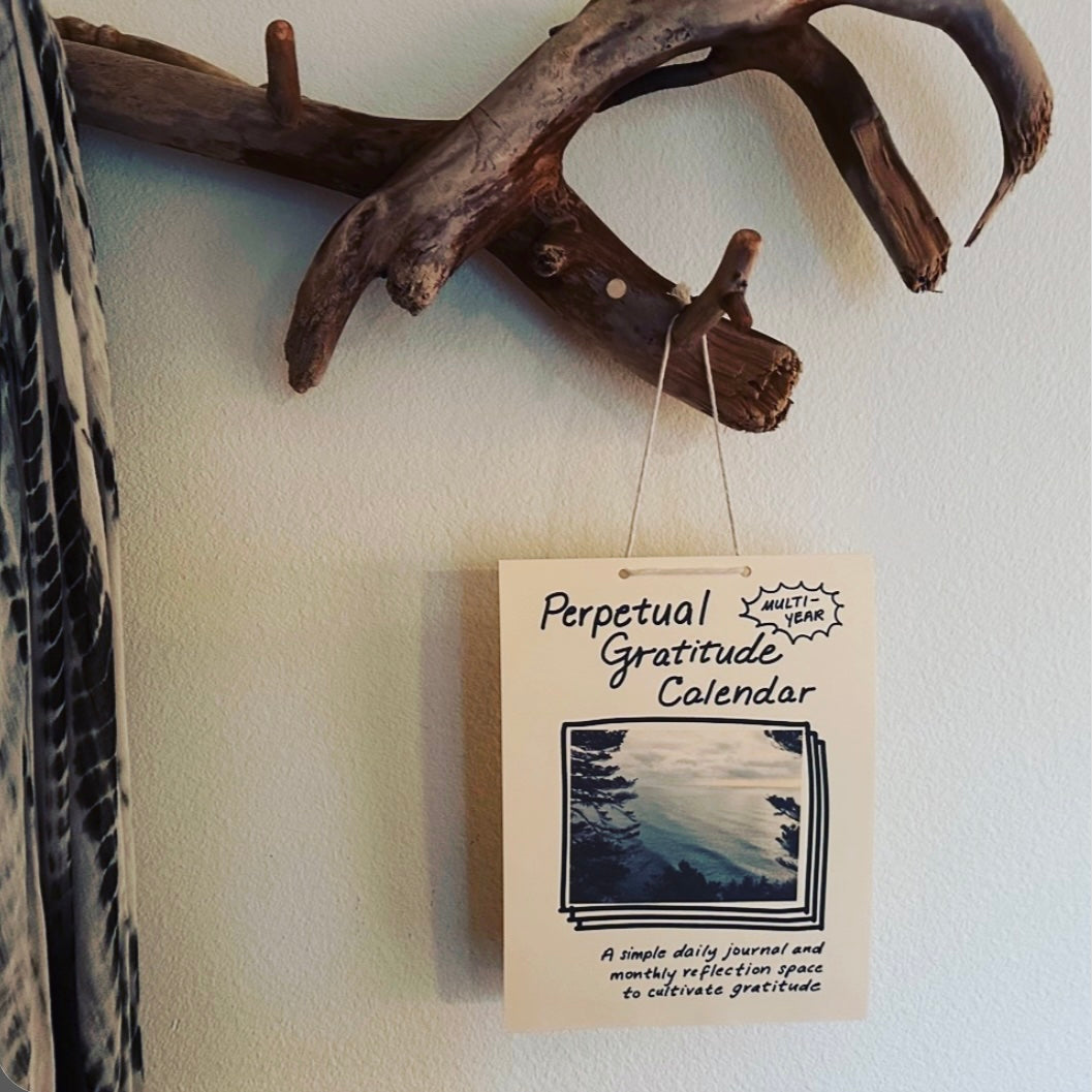 Perpetual Gratitude Calendar hanging on a wall with driftwood decor.
