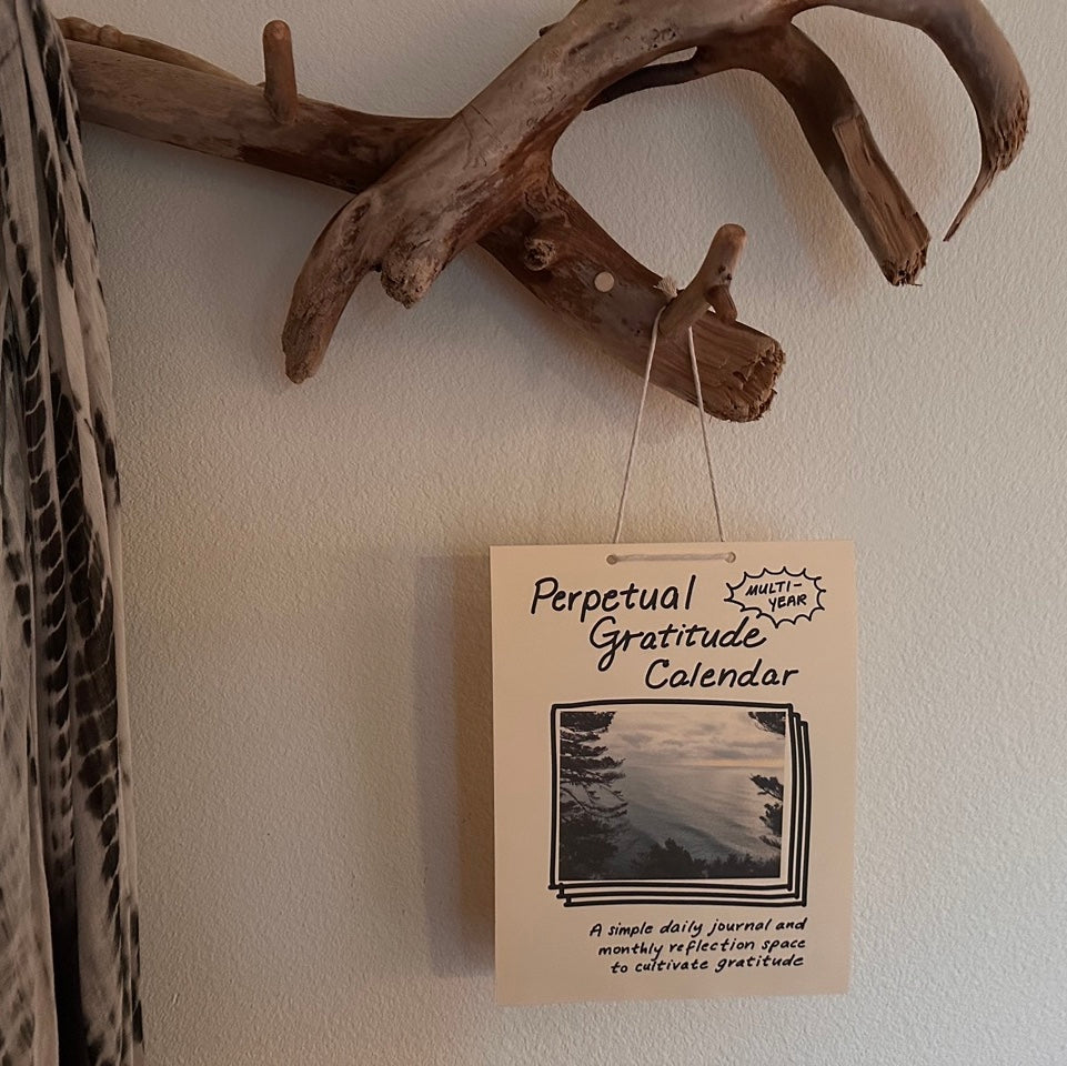 Perpetual Gratitude Calendar hanging on a wall with driftwood decor.