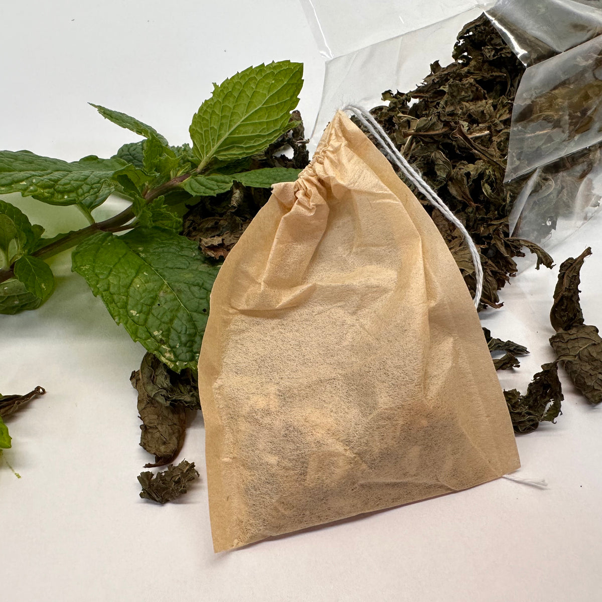 Tea bag with dried leaves and mint leaves on a white background
