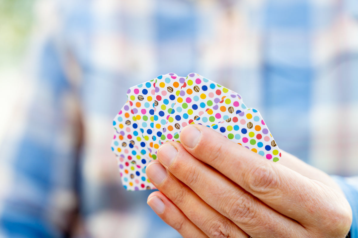 Close-up of a person&#39;s hand holding a fanned set of small micro sized domino playing cards