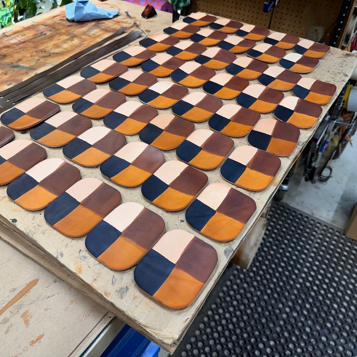 A work bench covered with square pieces of leather, each divided into four colors: natural, honey, dark brown and black