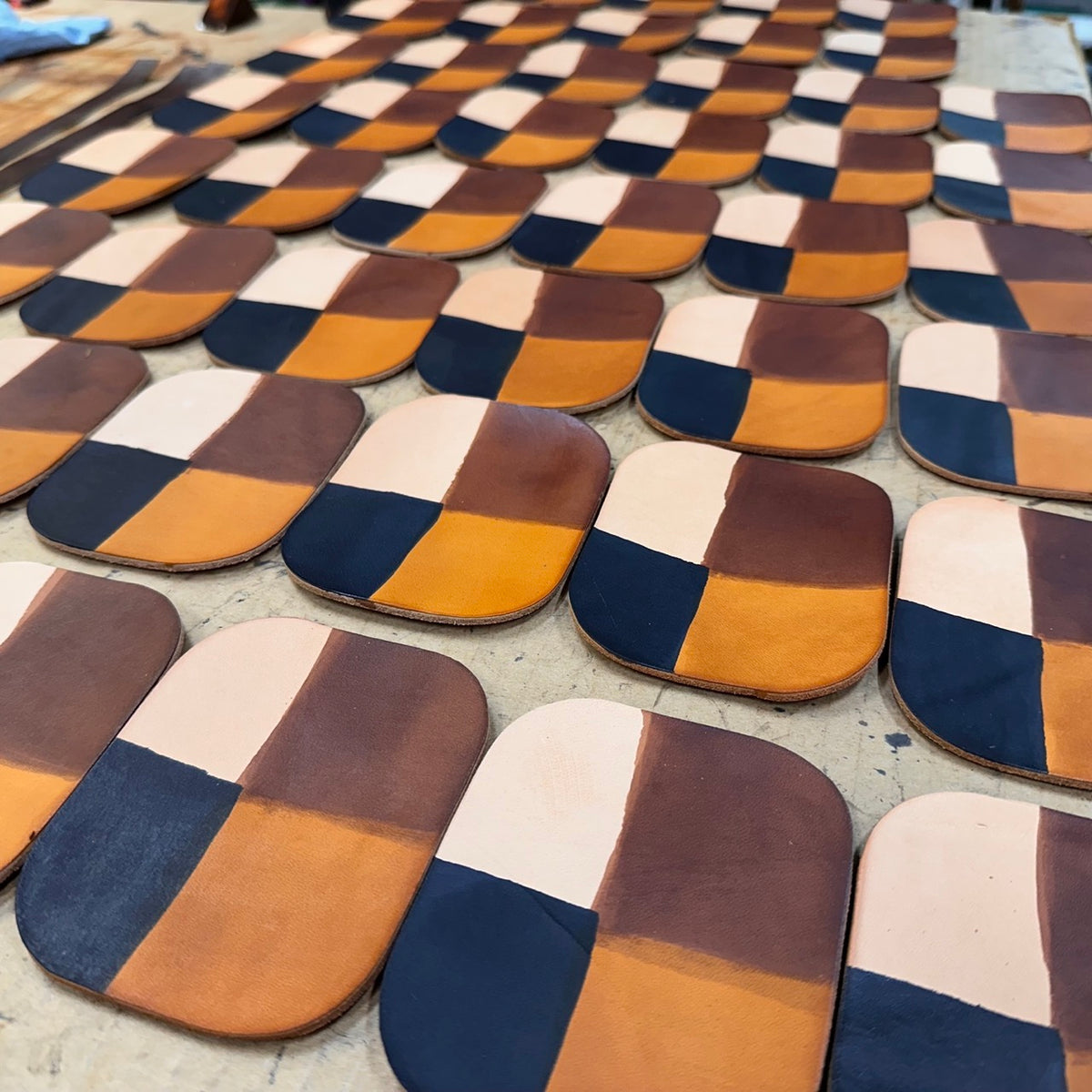 Close-up of A work surface covered with square pieces of leather, each divided into four colors: natural, honey, dark brown and black