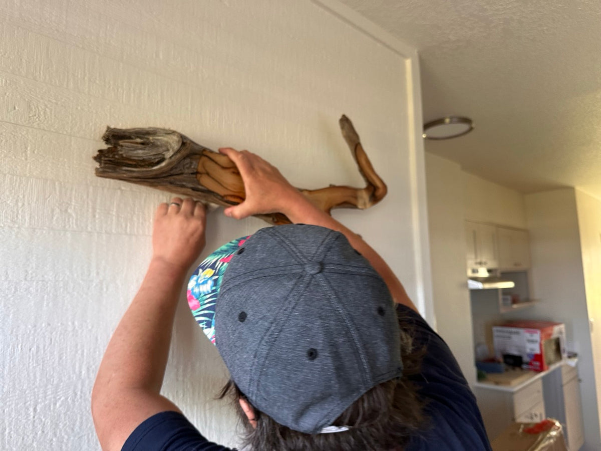 Person hanging a piece of driftwood on a wall