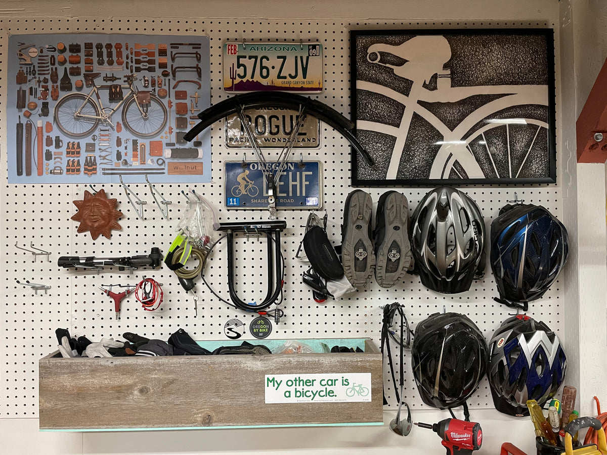 Customer photo of Walnut Studiolo Jim Golden Art Poster on pegboard display wall filled with bicycle memorabilia and bike gear like helmets, locks, and tire pumps