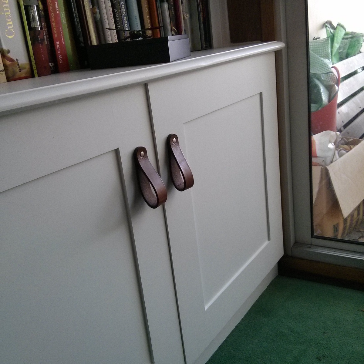 Customer photo of Honey Hawthorne leather handles installed on white cabinetry. The customer chose not  to use the washer for a different hardware look.