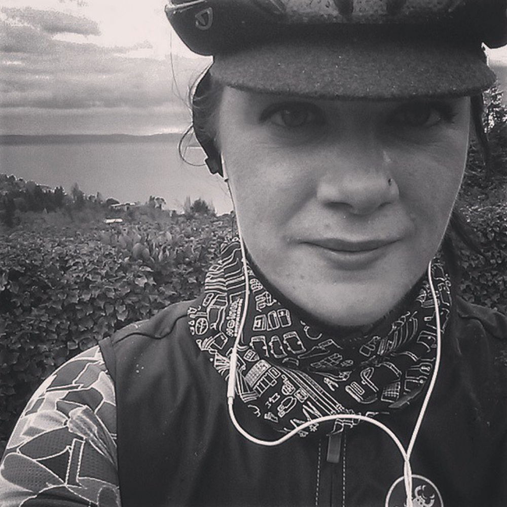 Black and white image of a woman in a bicycle helmet wearing the black version of the bicycle print bandana around her neck.