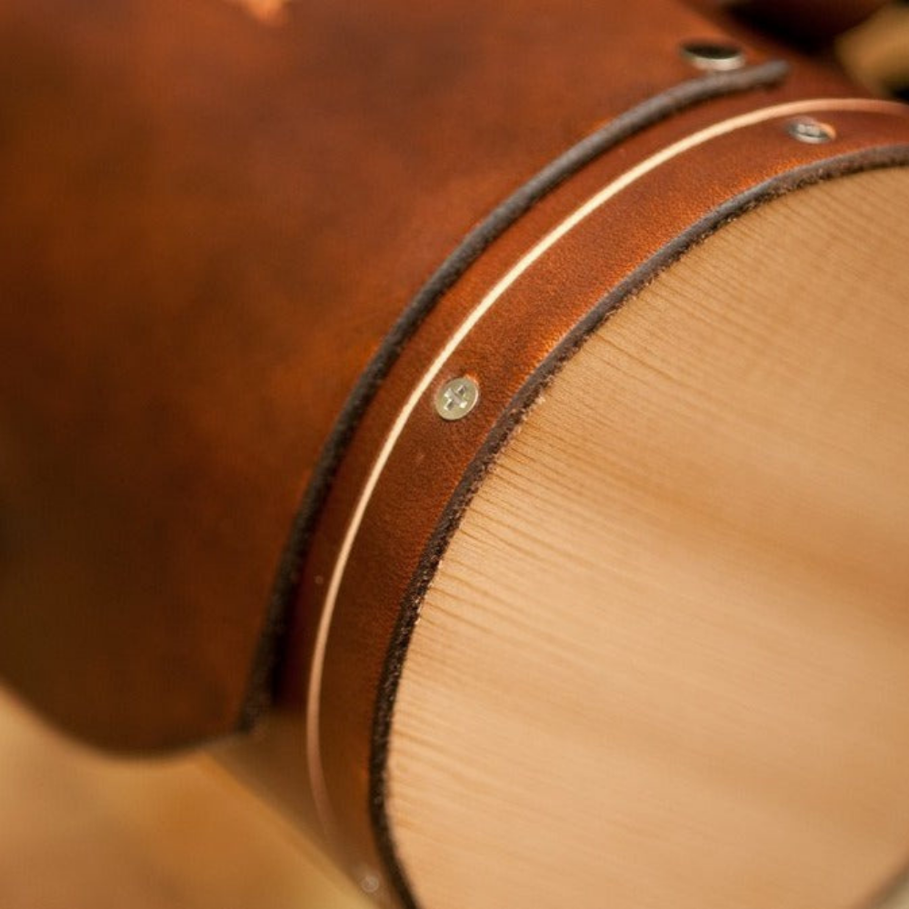 Close-up details of wooden end pieces attachment to honey leather handlebar barrel bag.
