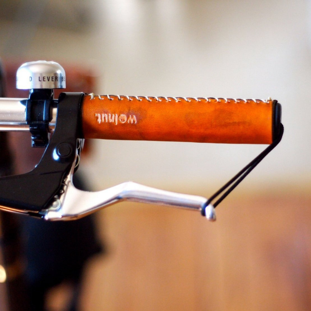 Close-up photo of a honey leather bicycle grip with white stitching sewn on to a bicycle mountain bike handlebar