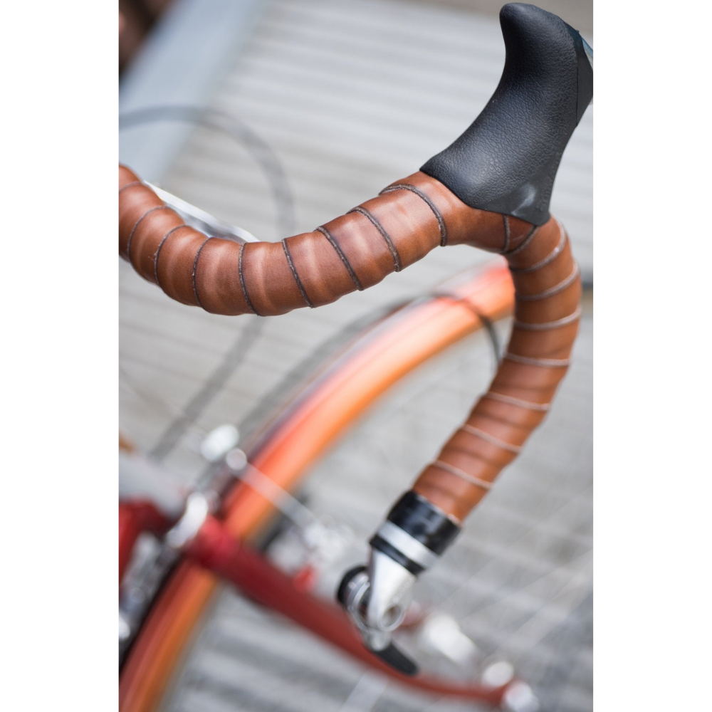 Bird&#39;s eye view looking down at bicycle drop bars that are wrapped in dark brown vegetable-tanned leather