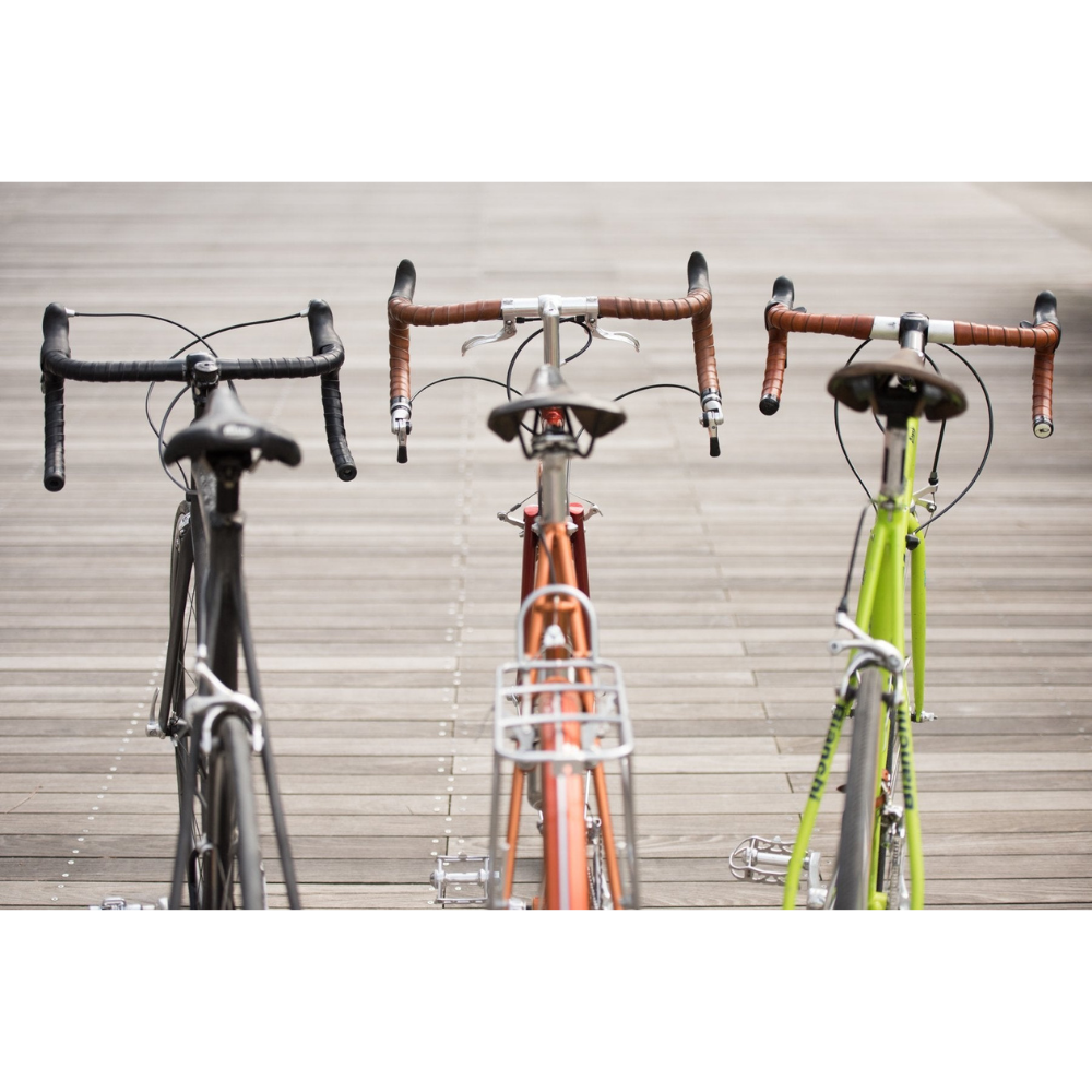 Viewed from behind, three bicycles lined up in a row in different colors with different color handlebar wraps: Honey, Dark Brown, and Black leather