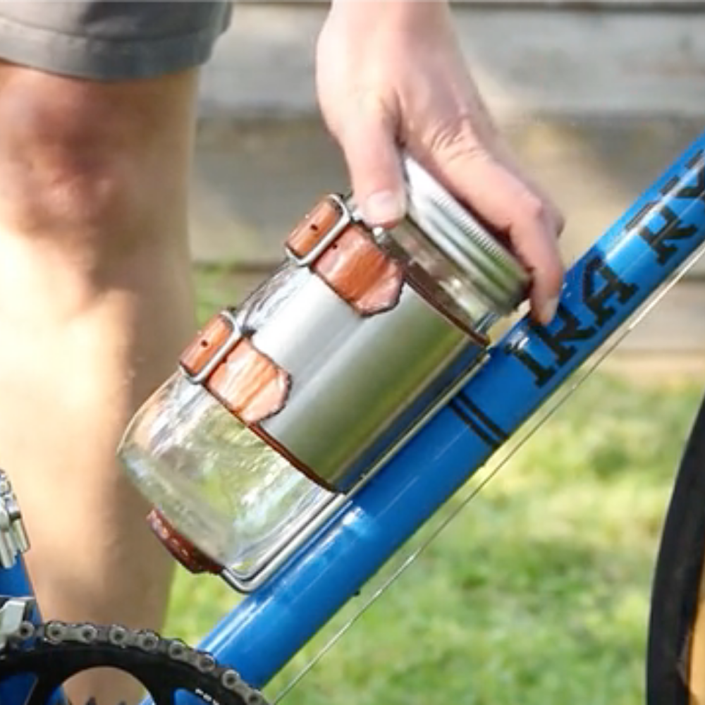 Person latching clear glass jar into the upcycle cage mounted drink holder