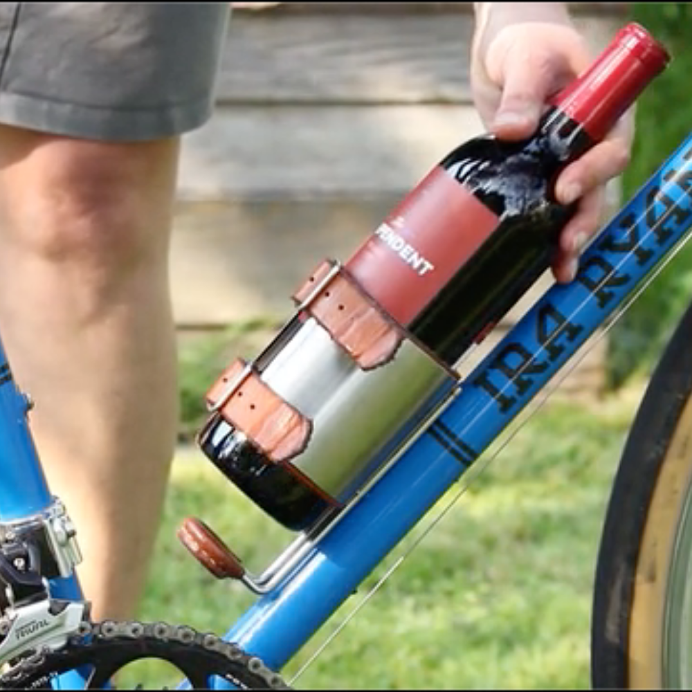 Person latching wine bottle into the upcycle cage mounted onto bike frame