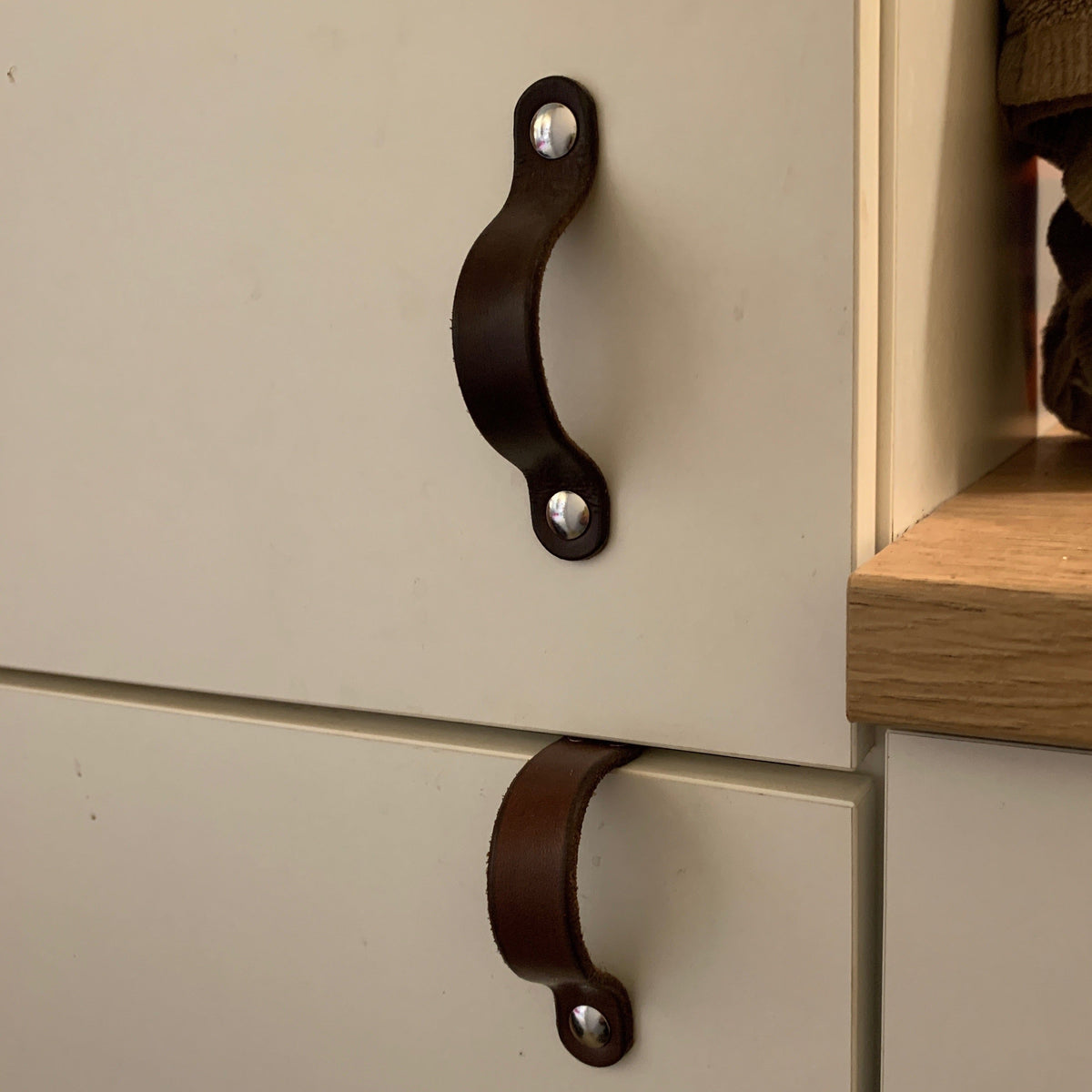 Customer Photo of a Dark Brown Leather Flanders Handle with Nickel Hardware on a White Bathroom Cabinet Door from IKEA Above a Lovejoy Dark Brown Handle on the Cabinet Below