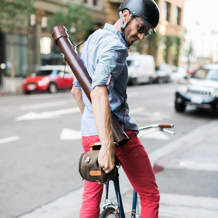 Man adjusting his bike satchel while wearing dark brown blueprint tube